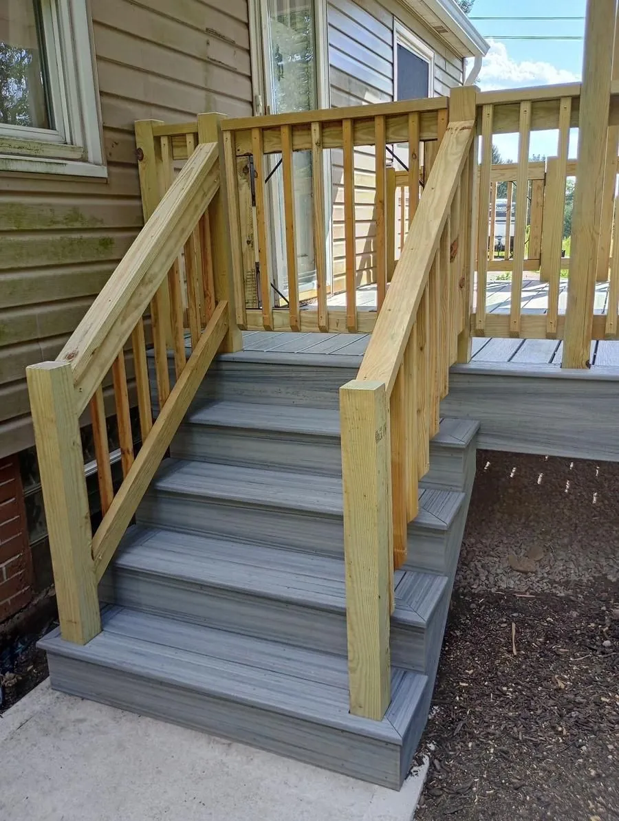 Composite deck stairs with pressure-treated wood railing, side view showing landing