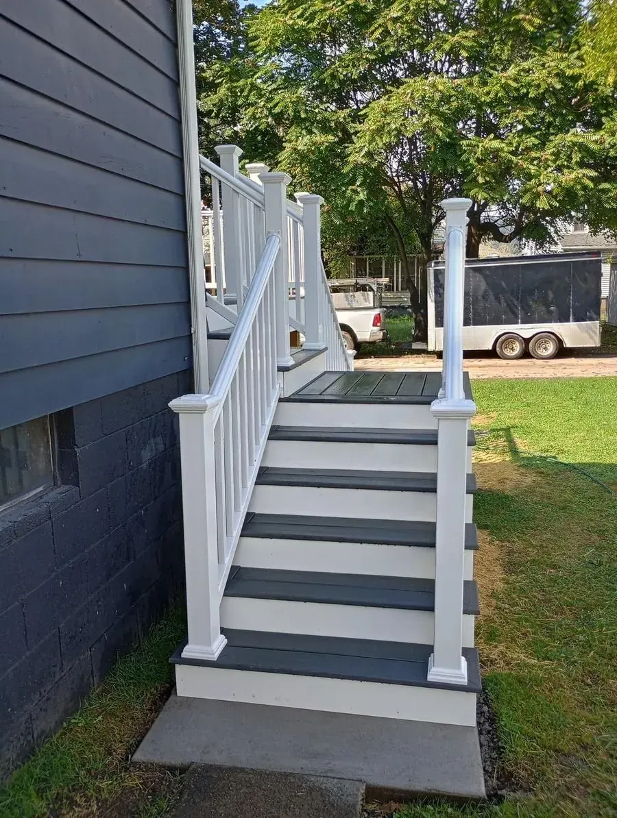 Deck entry stairs with dark composite treads, white risers, and white vinyl railing system