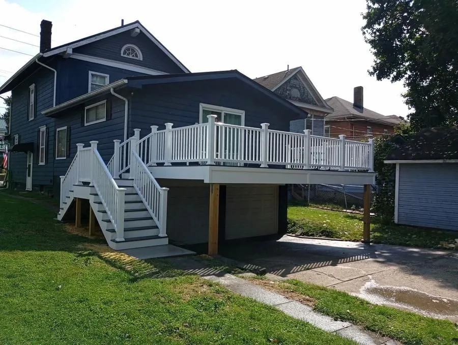 Large elevated composite deck with white vinyl railing over garage, full exterior view