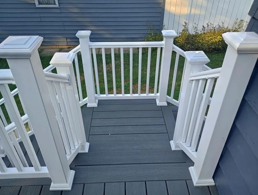 Close-up of composite deck landing with white vinyl post caps and railing detail