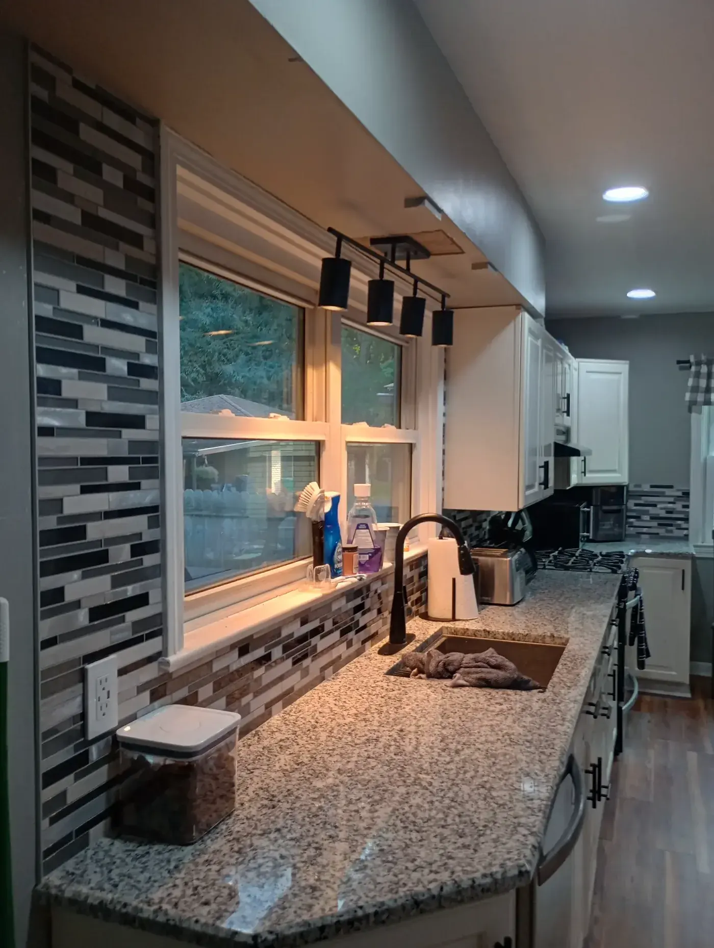 Kitchen remodel with granite countertops, mosaic tile backsplash and black pendant lights over island