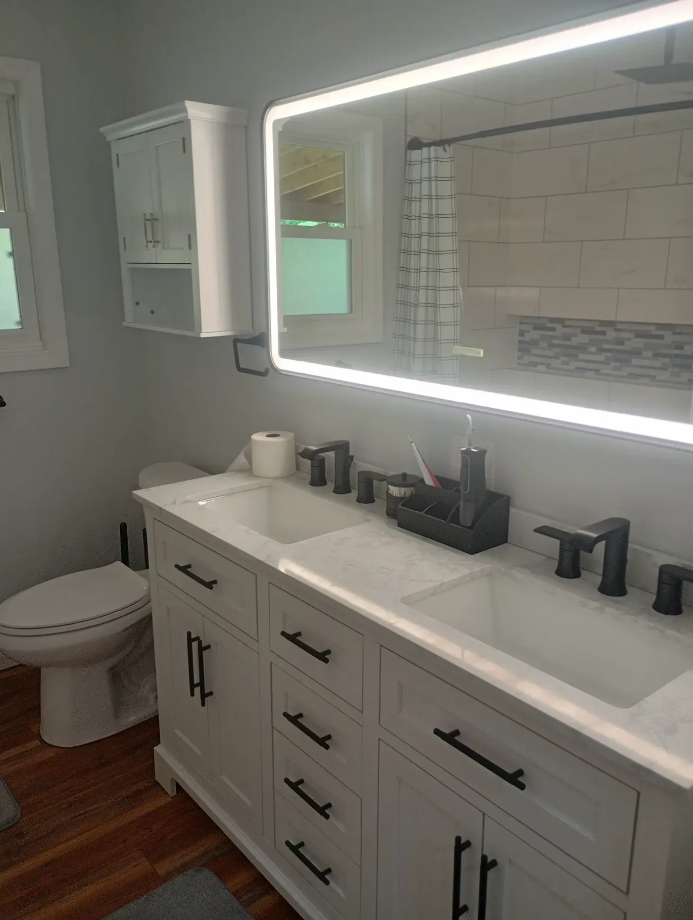 Bathroom double vanity with LED backlit mirror, marble countertop and matte black hardware