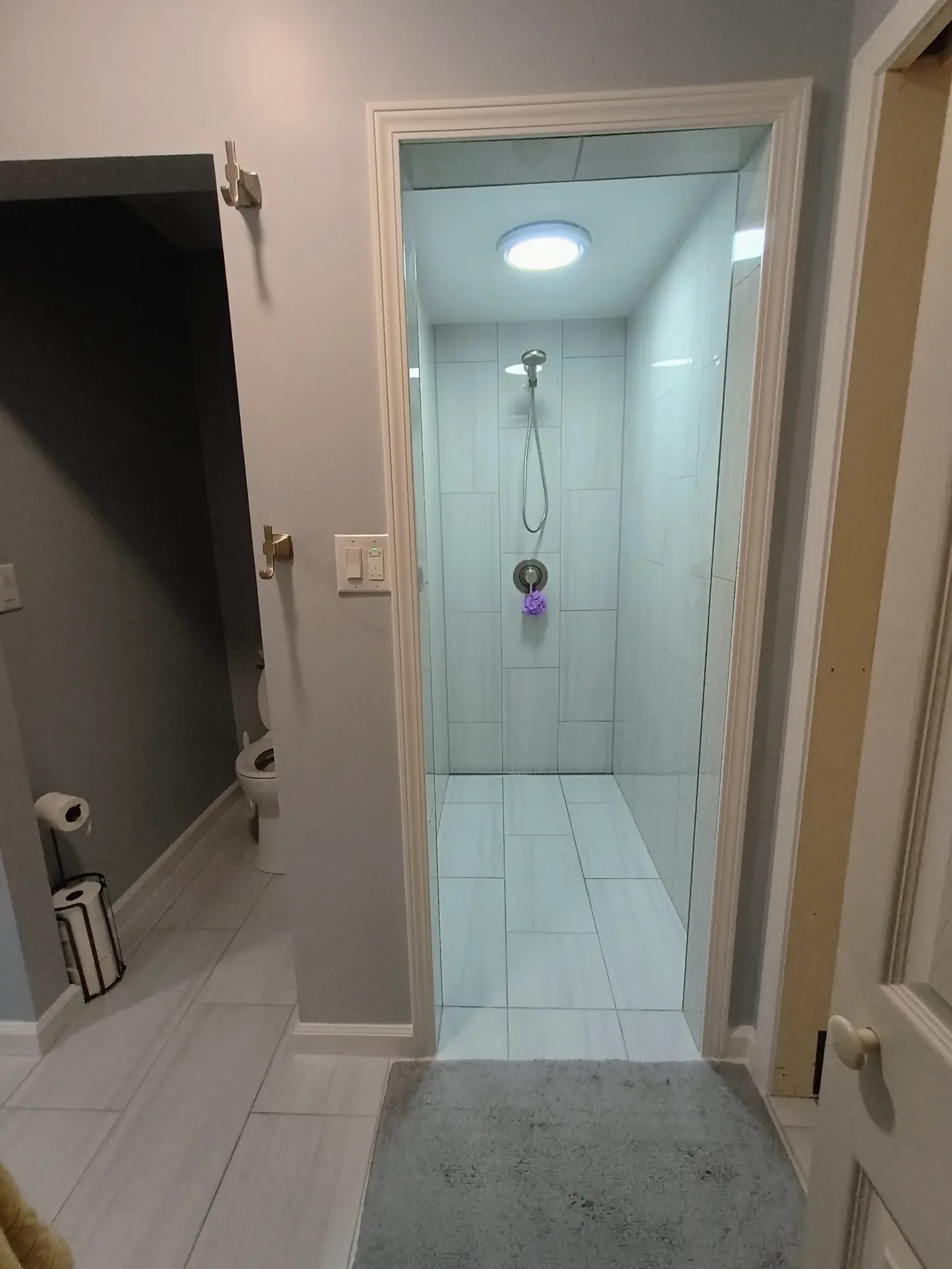 Walk-in shower with large format white tile walls and frameless glass door