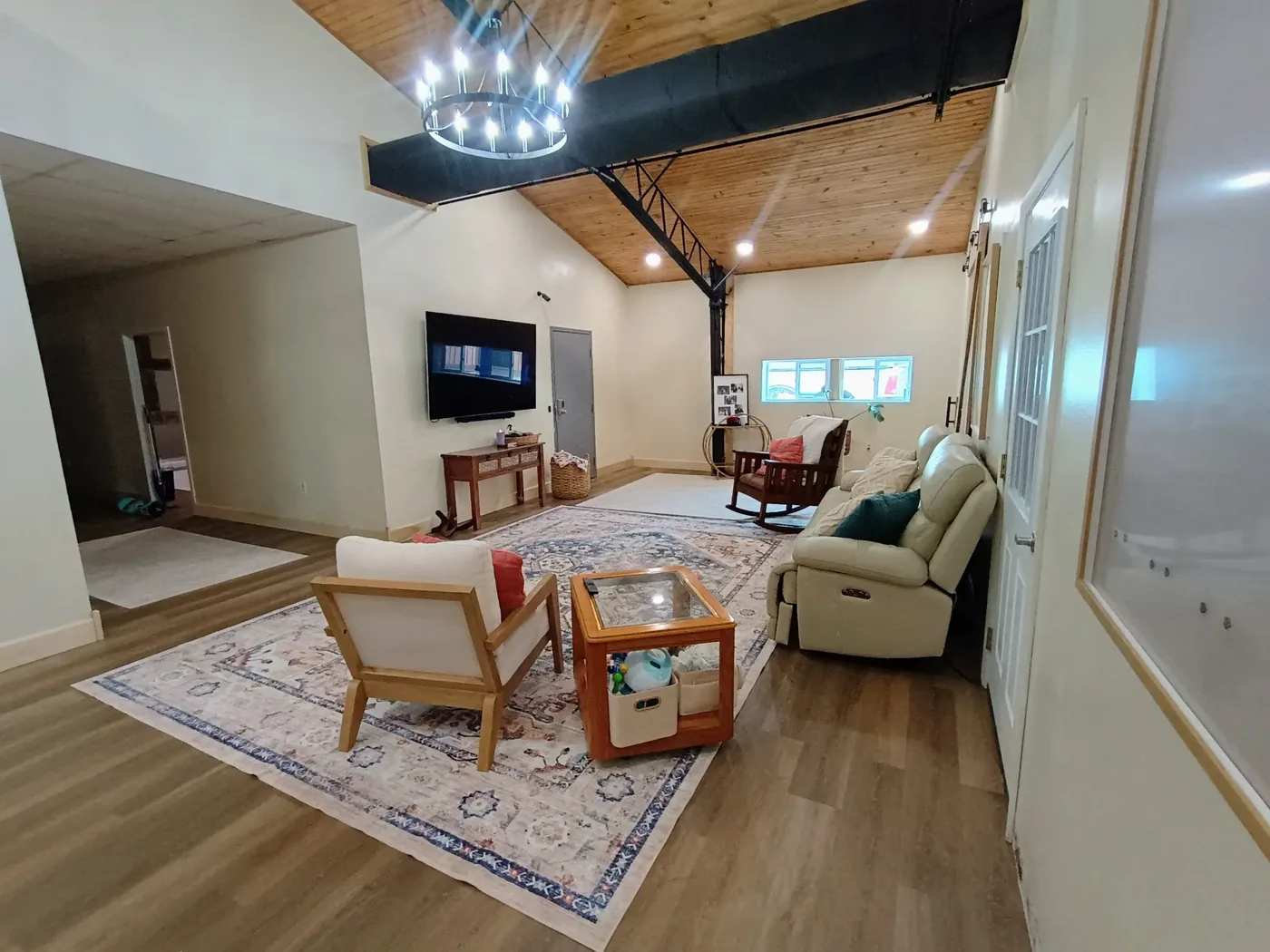 Home addition with vaulted knotty pine ceiling, exposed steel beams and chandelier