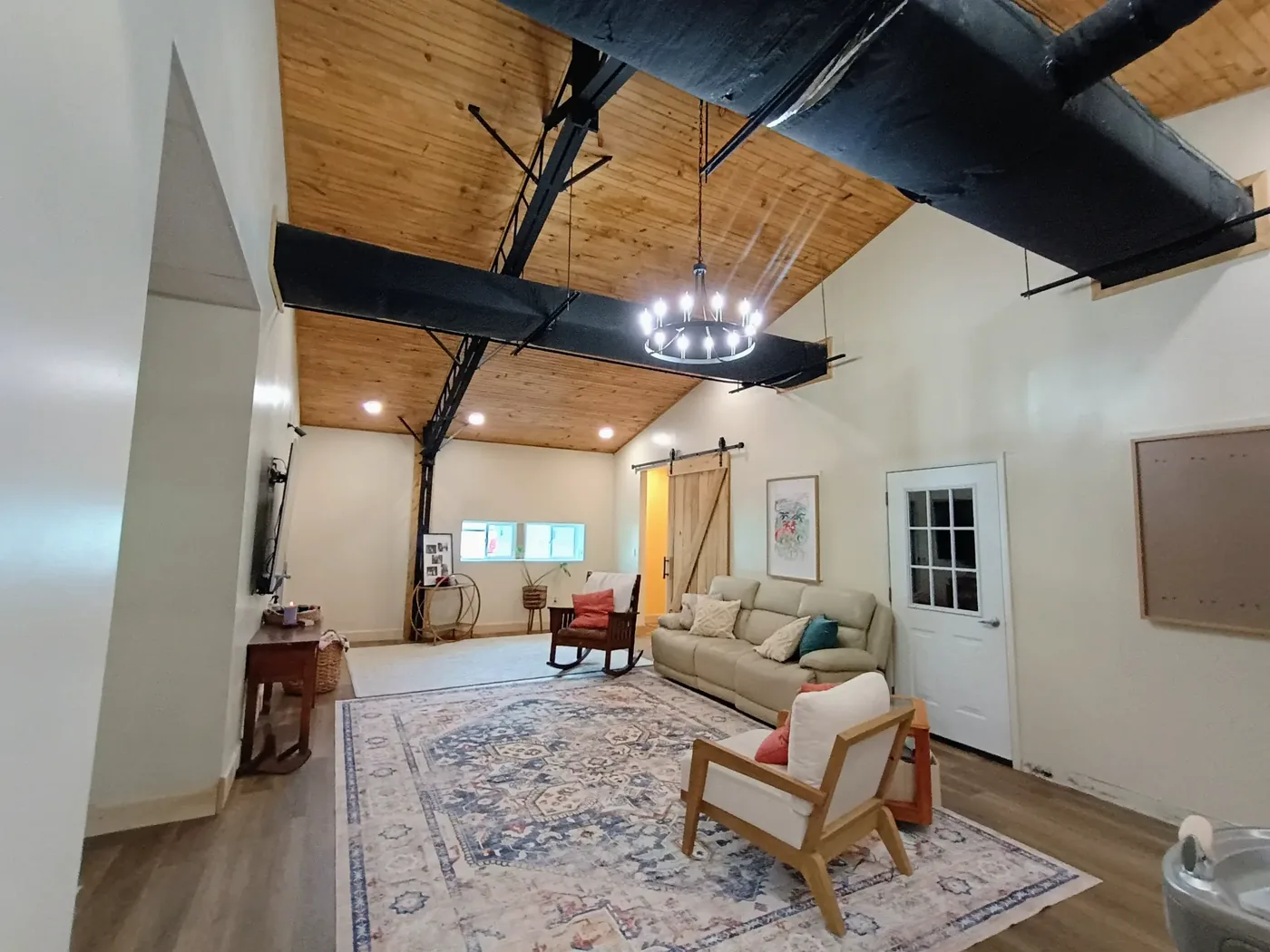 Home addition interior with sliding barn door, vaulted ceiling and exposed steel trusses